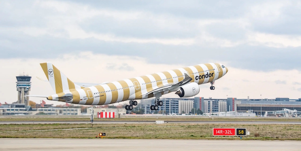 Yellow and white striped Condor Airlines airplane taking off from the runway.
