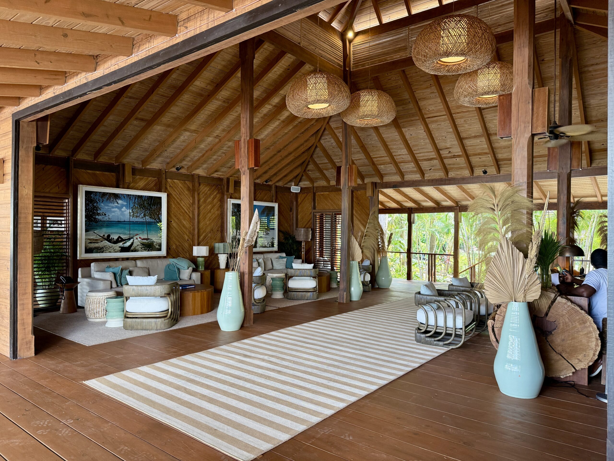 a room with wood furnishings, couches, armchairs and a long, striped rug