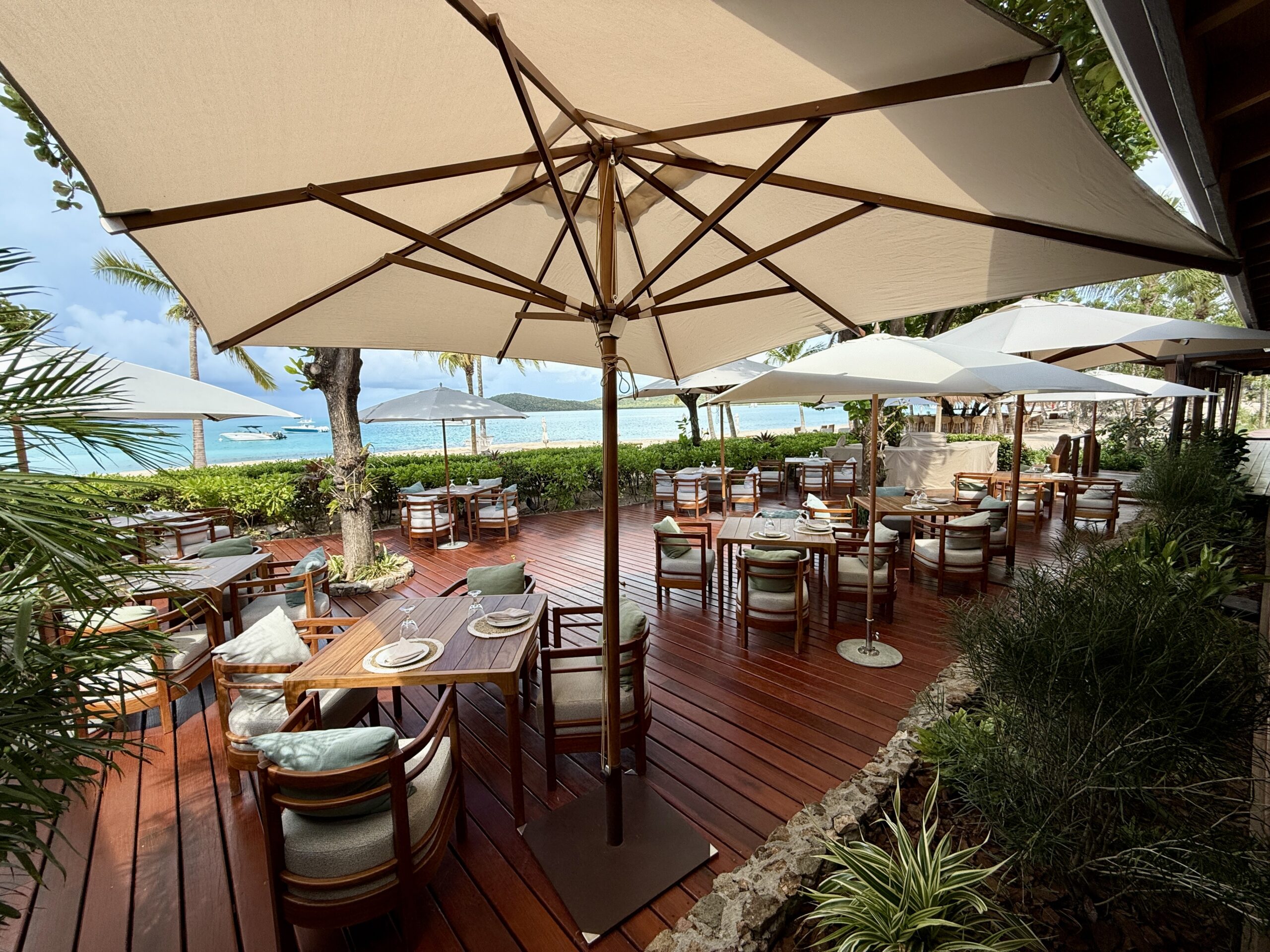 tables on a wooden deck with large umbrellas overhead