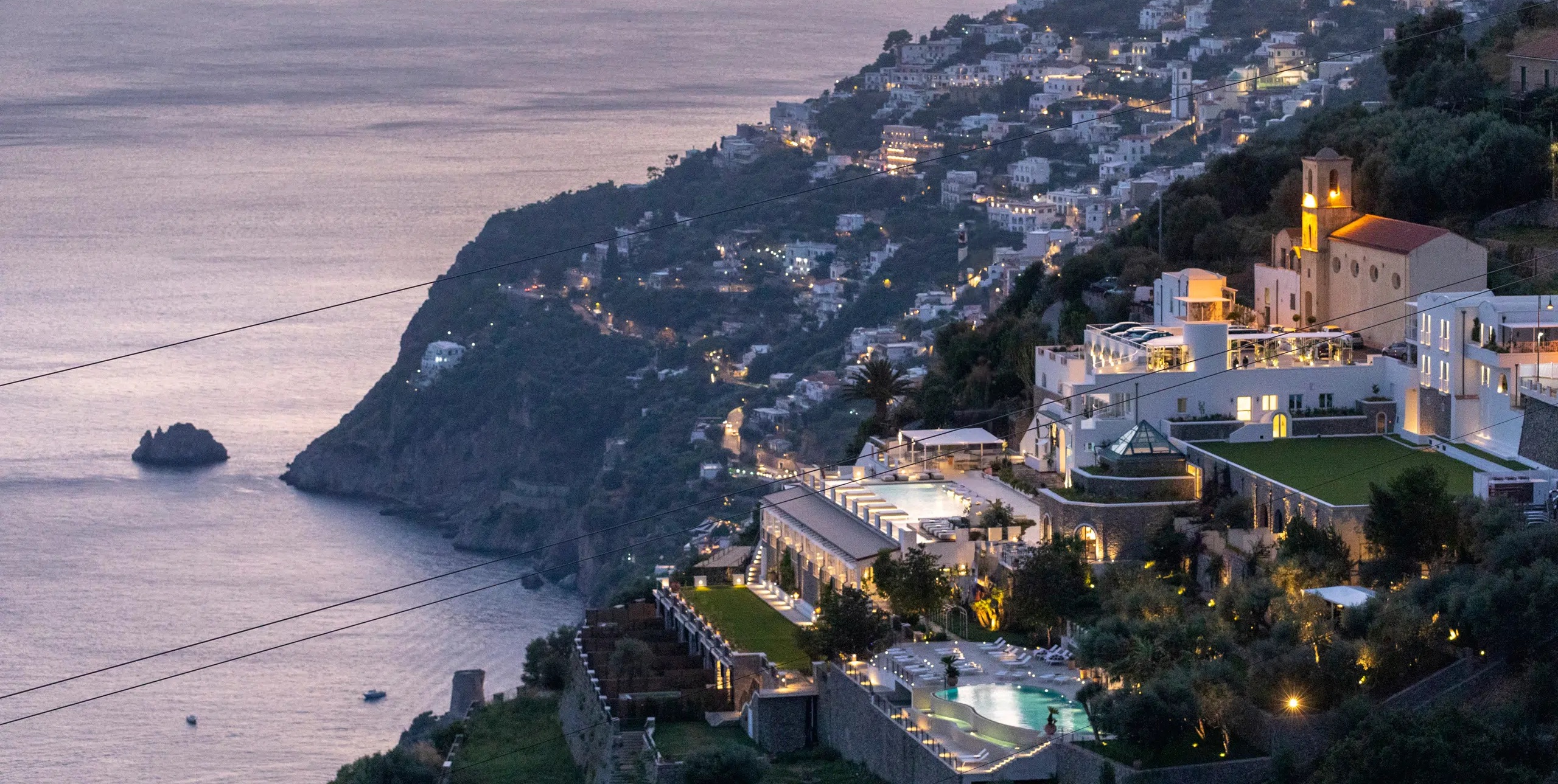 hotel buildings and a pool built into a hill overlooking the ocean