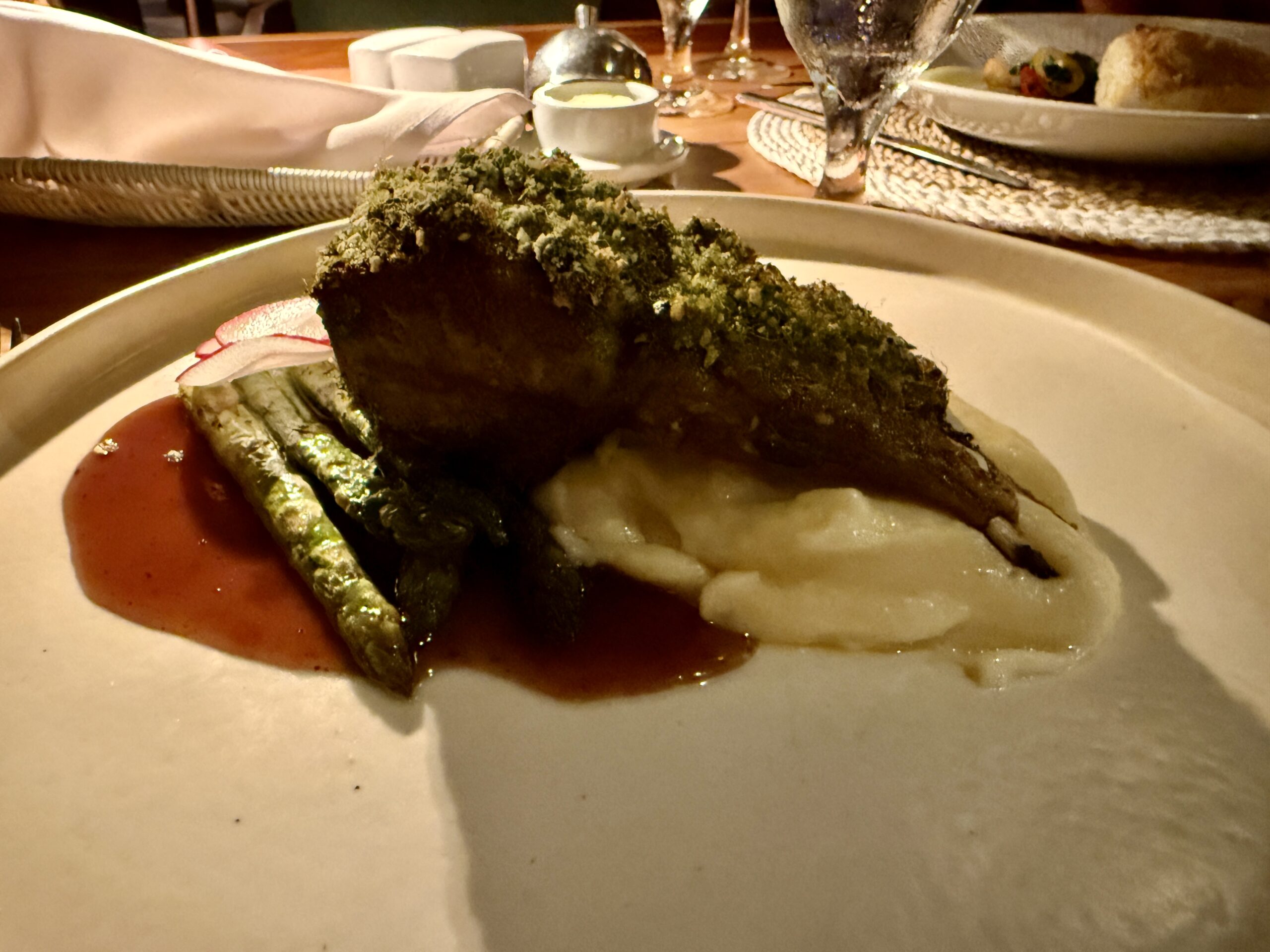 a rack of lamb served over mashed potatoes with asparagus