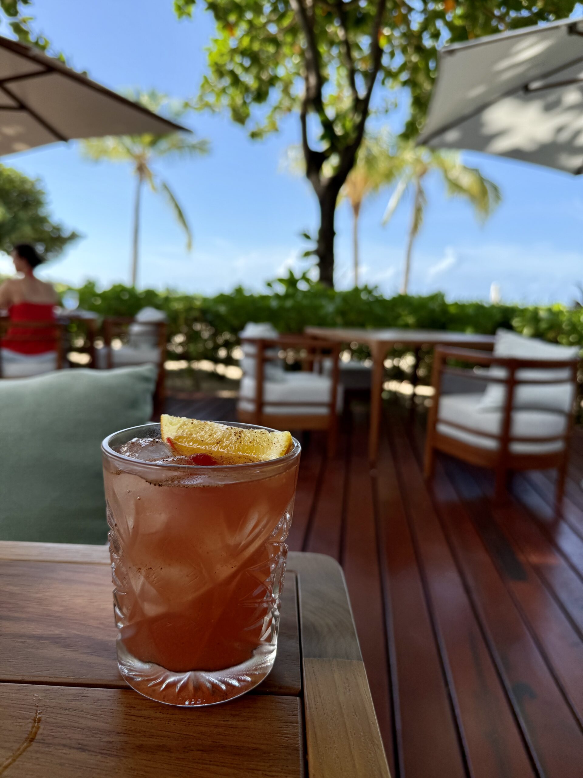 a glass cocktail full of red liquid sitting ona table