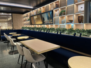 cafe seating and tables along a blue bench with green plants growing behind it