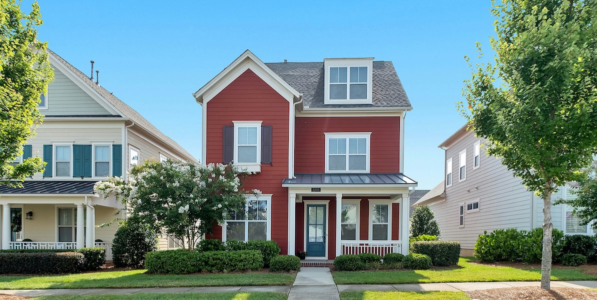 a red house with trees and two neighboring houses
