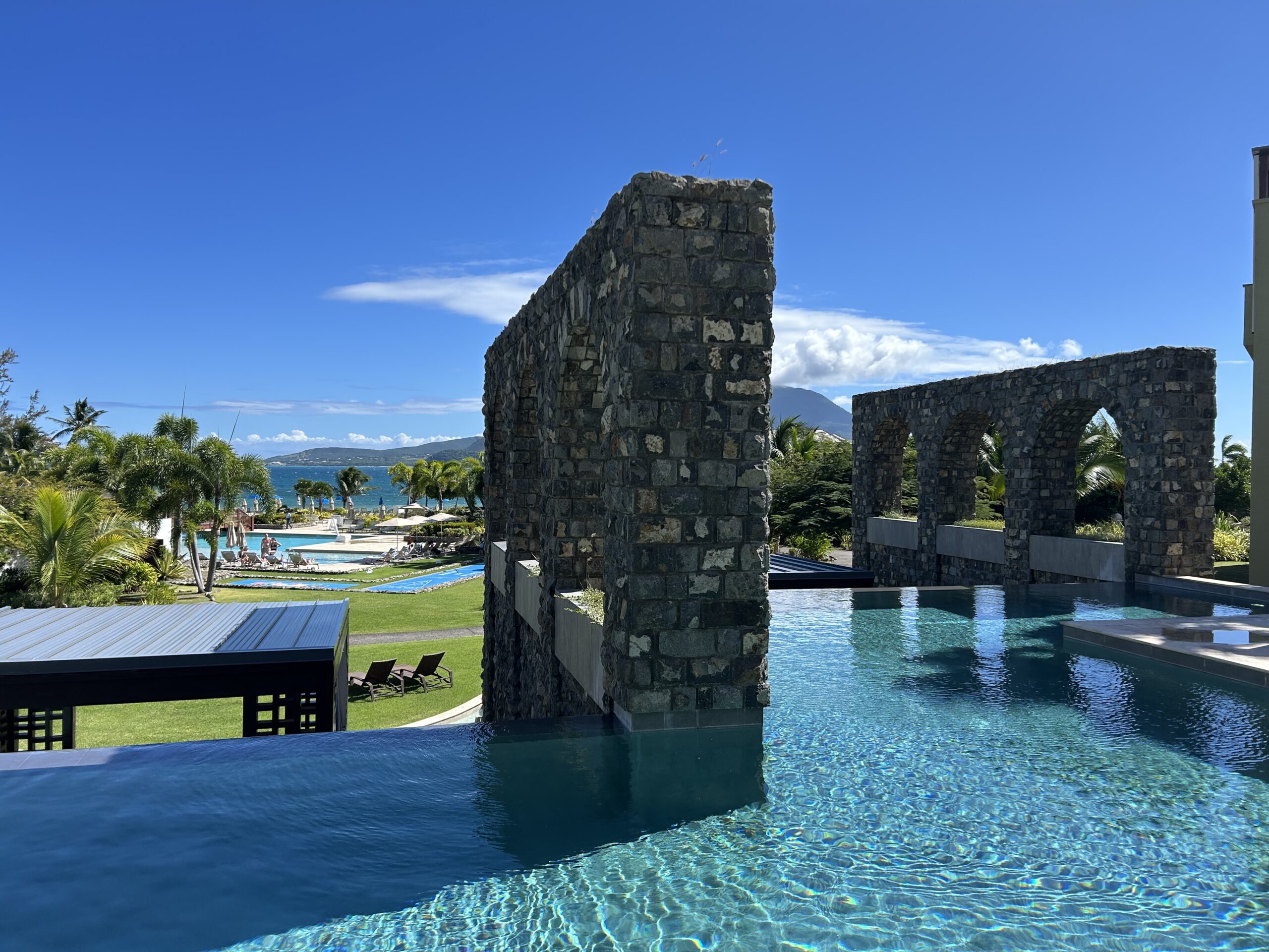 an swimming pool with an infinity edge and stone arches 