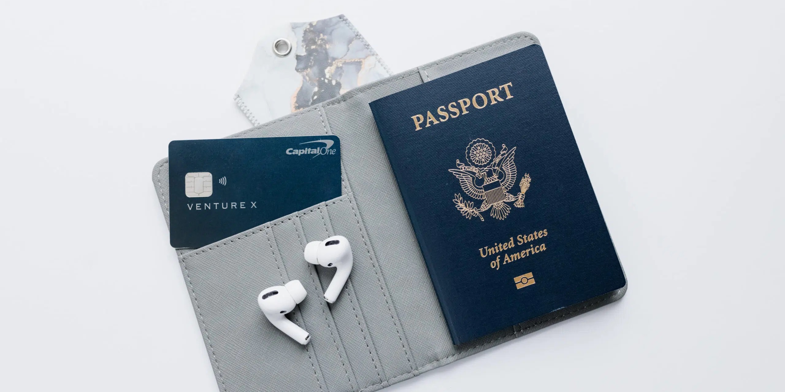 Capital One Venture X card in a wallet with passport and airpods.