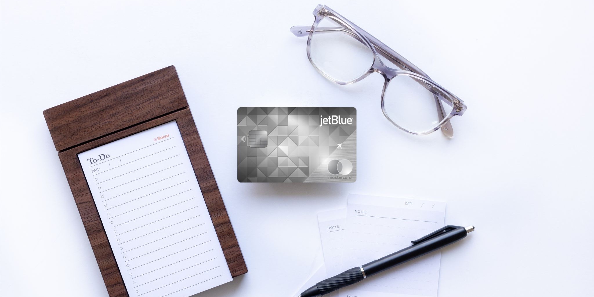 JetBlue Premier Card with Notepad, glasses, and a pen.