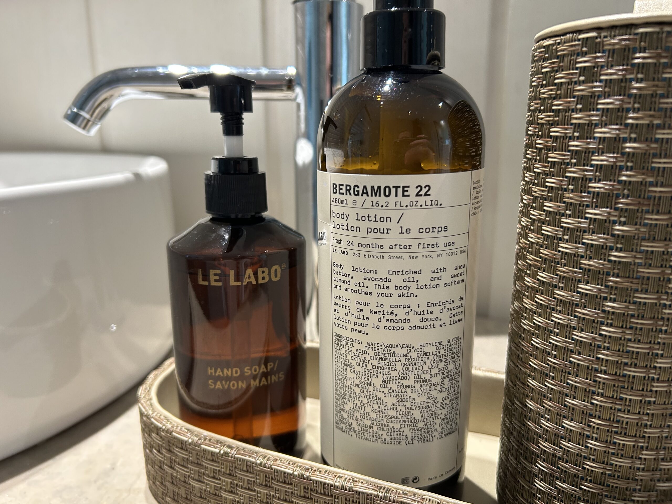 Le Labo soaps and lotions in a basket next to a sink 
