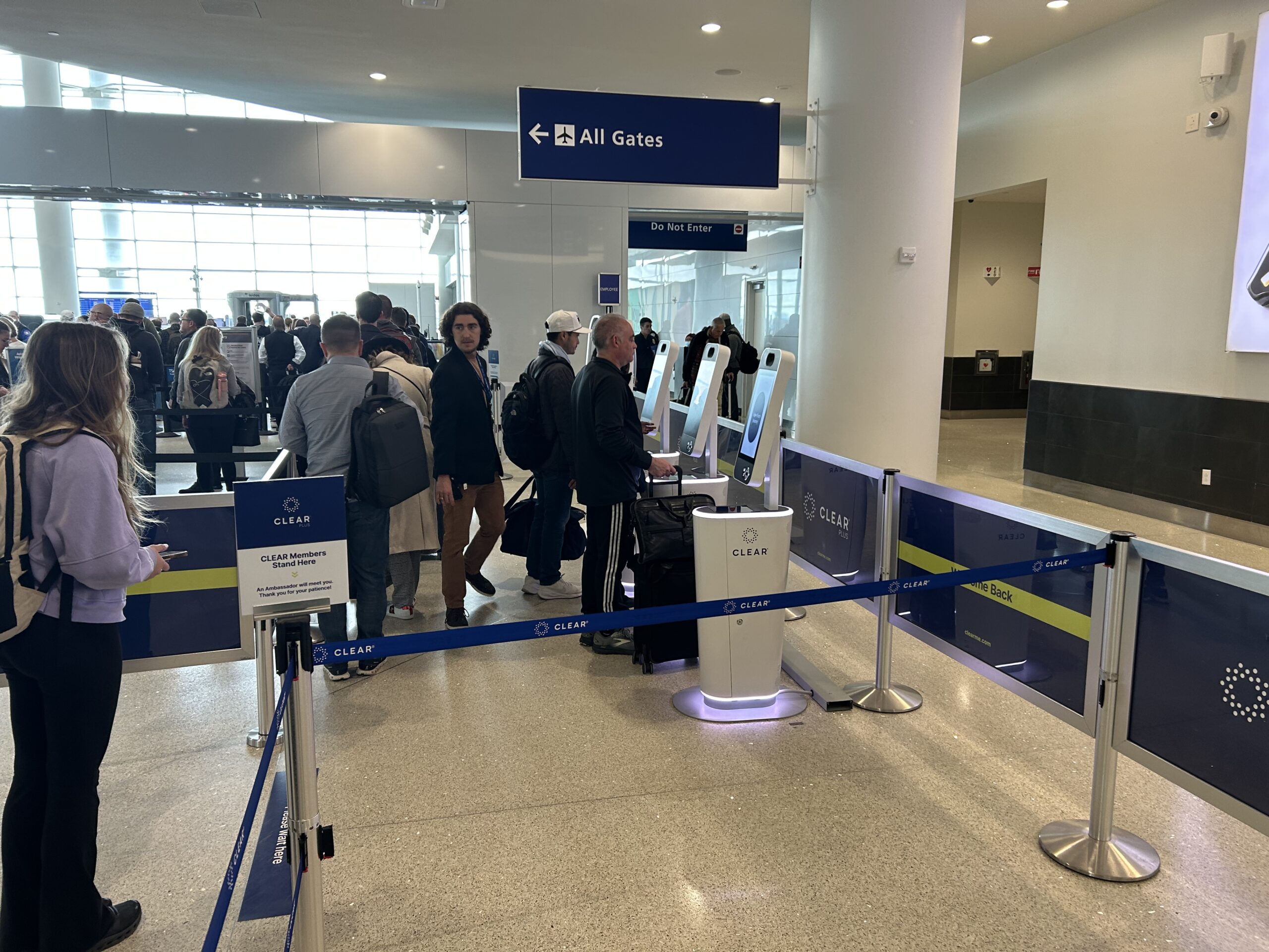 Travelers wait in line to use CLEAR security pods at airport security. 