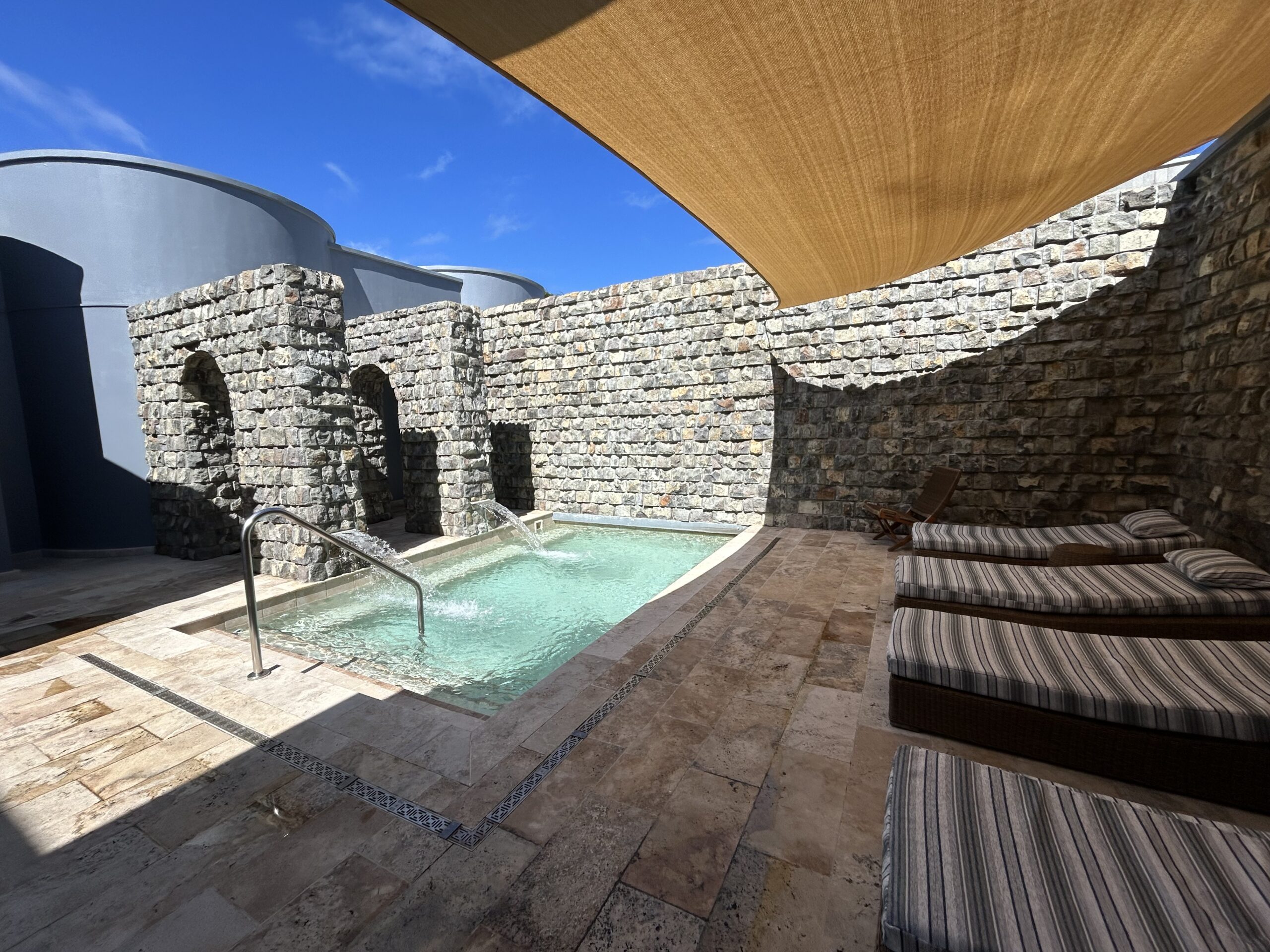 Plunge pool, lounge chairs, and stone arches.