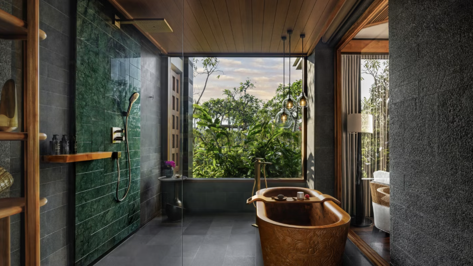 Hotel bathroom with a rainfall shower, a copper soaking tub, and a large glass window. 
