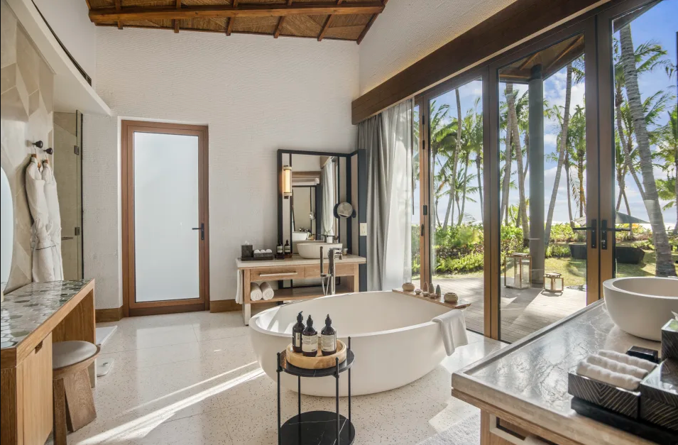 a hotel bathroom with a circular tub and double doors leading to a patio 