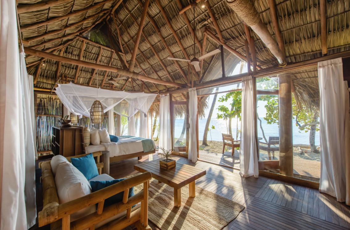 bed and a couch inside a hotel villa with an ocean view