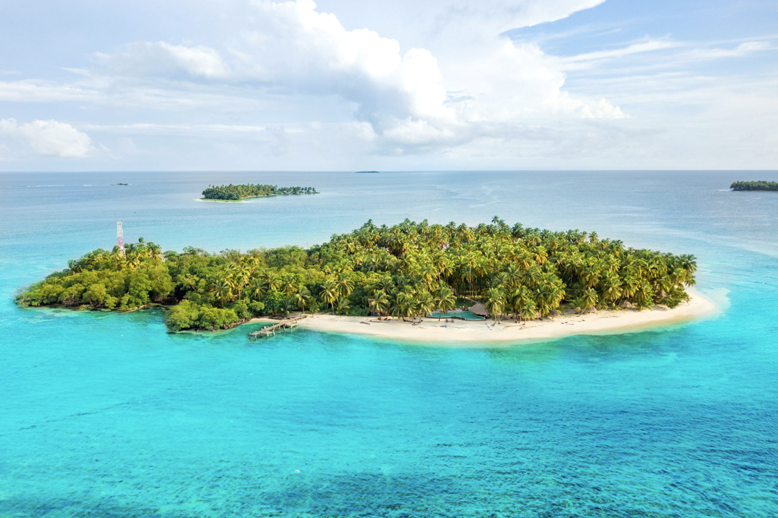 an island in the middle of the ocean covered with palm trees