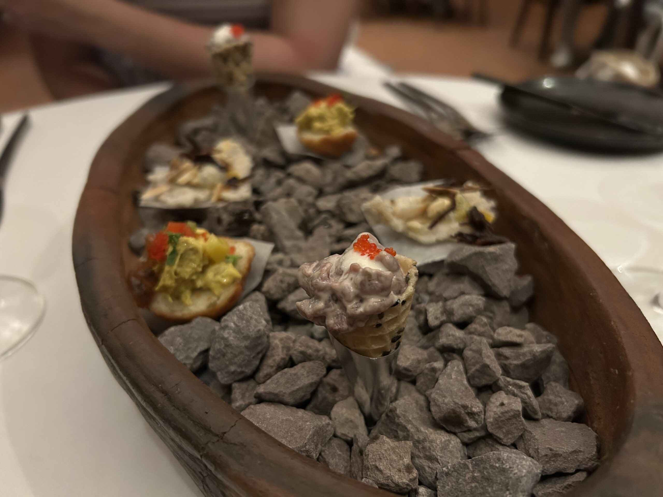 Stone House hor d'ourves in a bowl with rocks and a cone of food. 