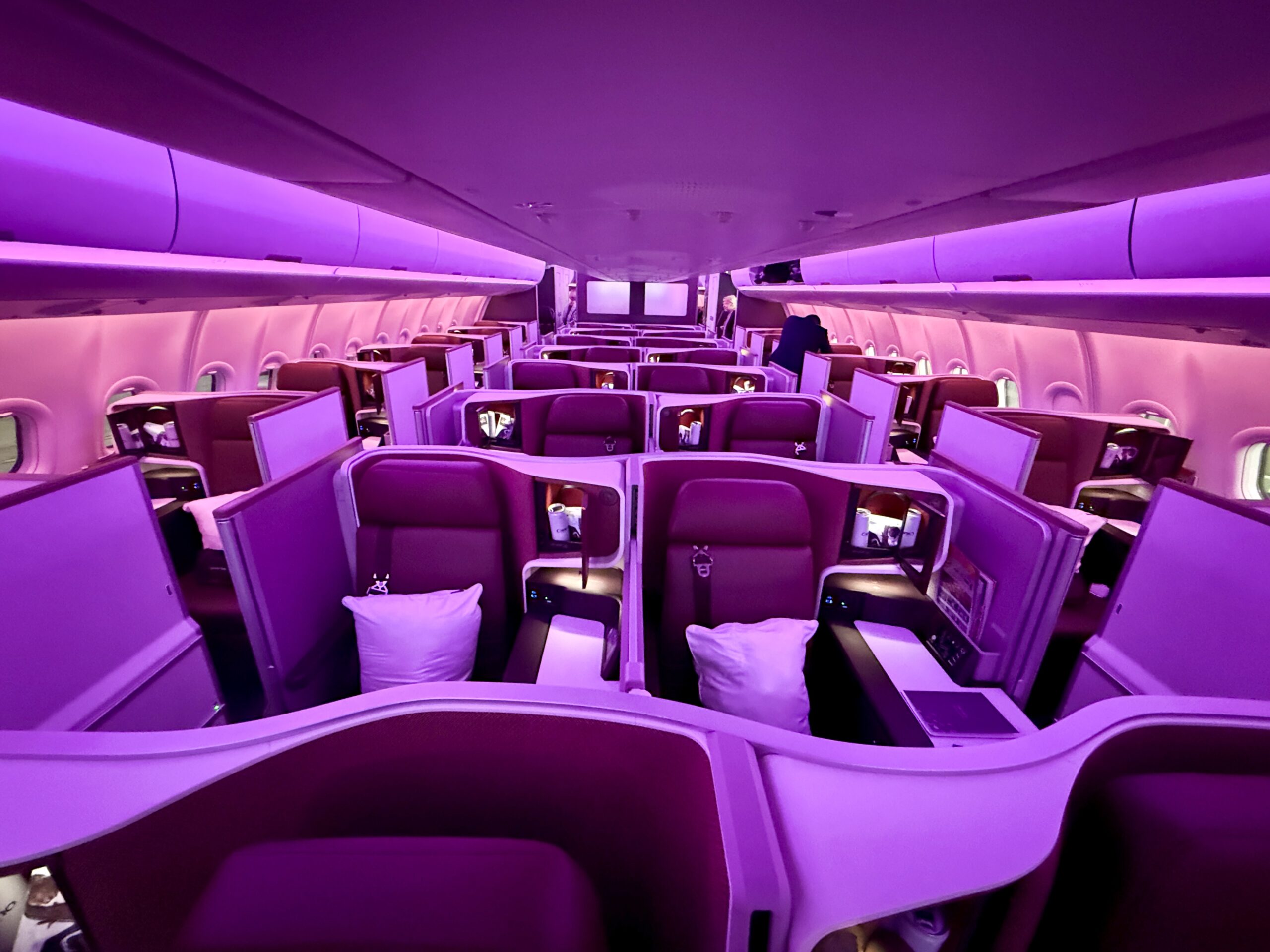 a business class cabin with purple and red lighting. 