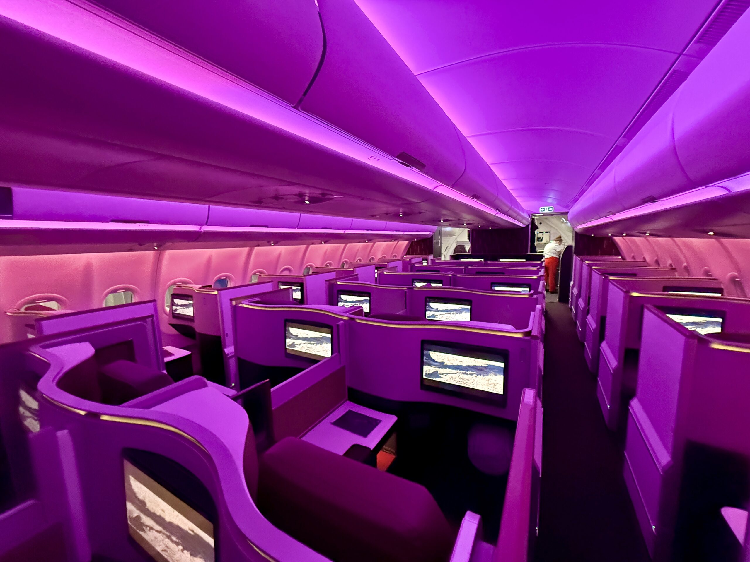 business class seats in a plane cabin with red and purple lighting