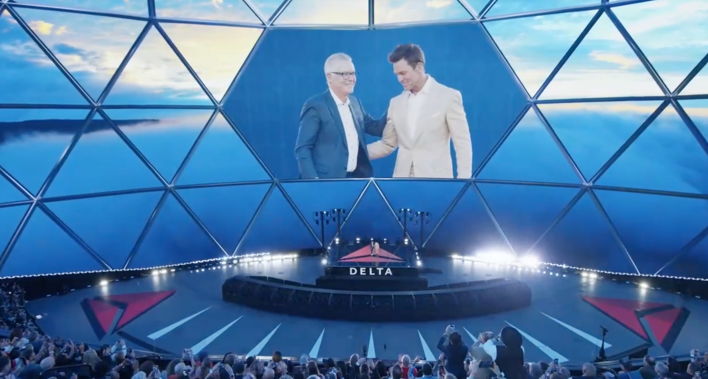 two men on a large stage with the delta logo