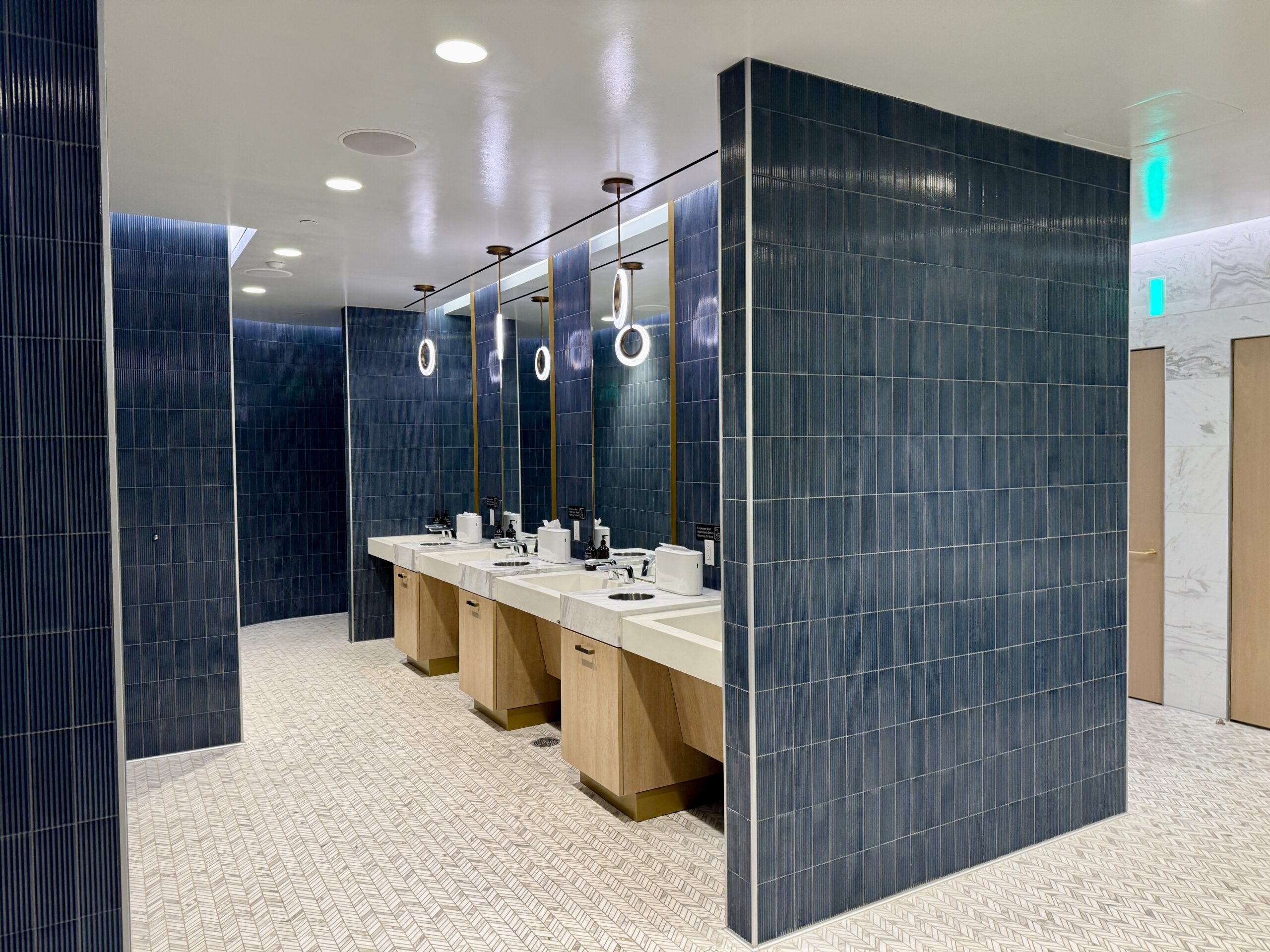 delta one lounge bathroom with sinks and blue tile walls
