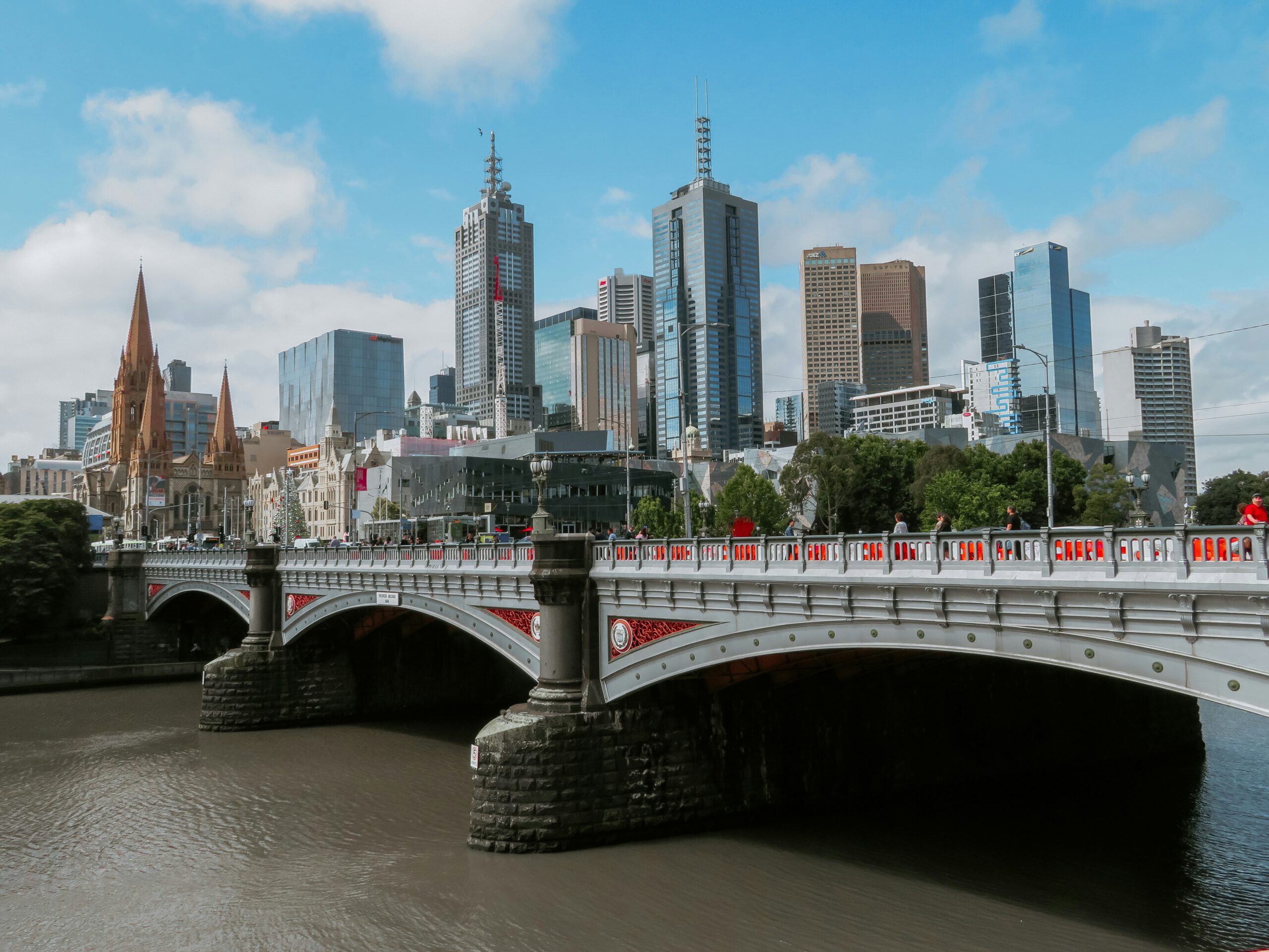 A bridge over a river leading to the city of Melbourne, Australia, with the city skyline in the background. 