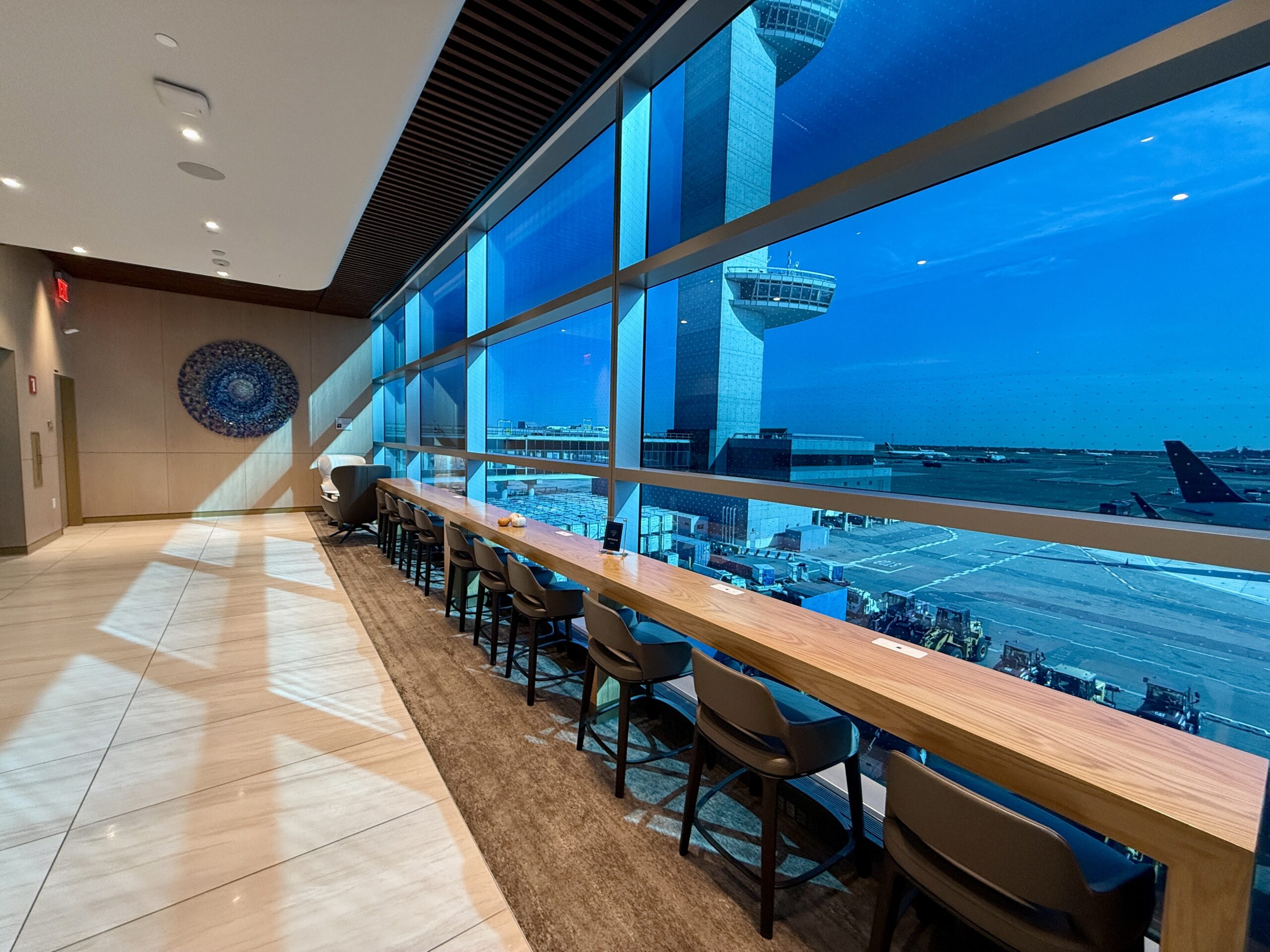 long table with chairs along blue-tined windows overlooking the tarmac