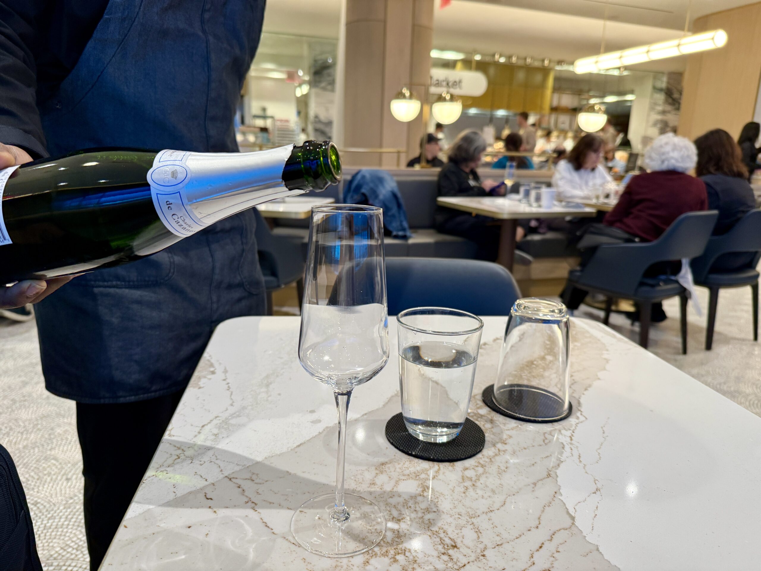 person pouring a glass of champagne at a table