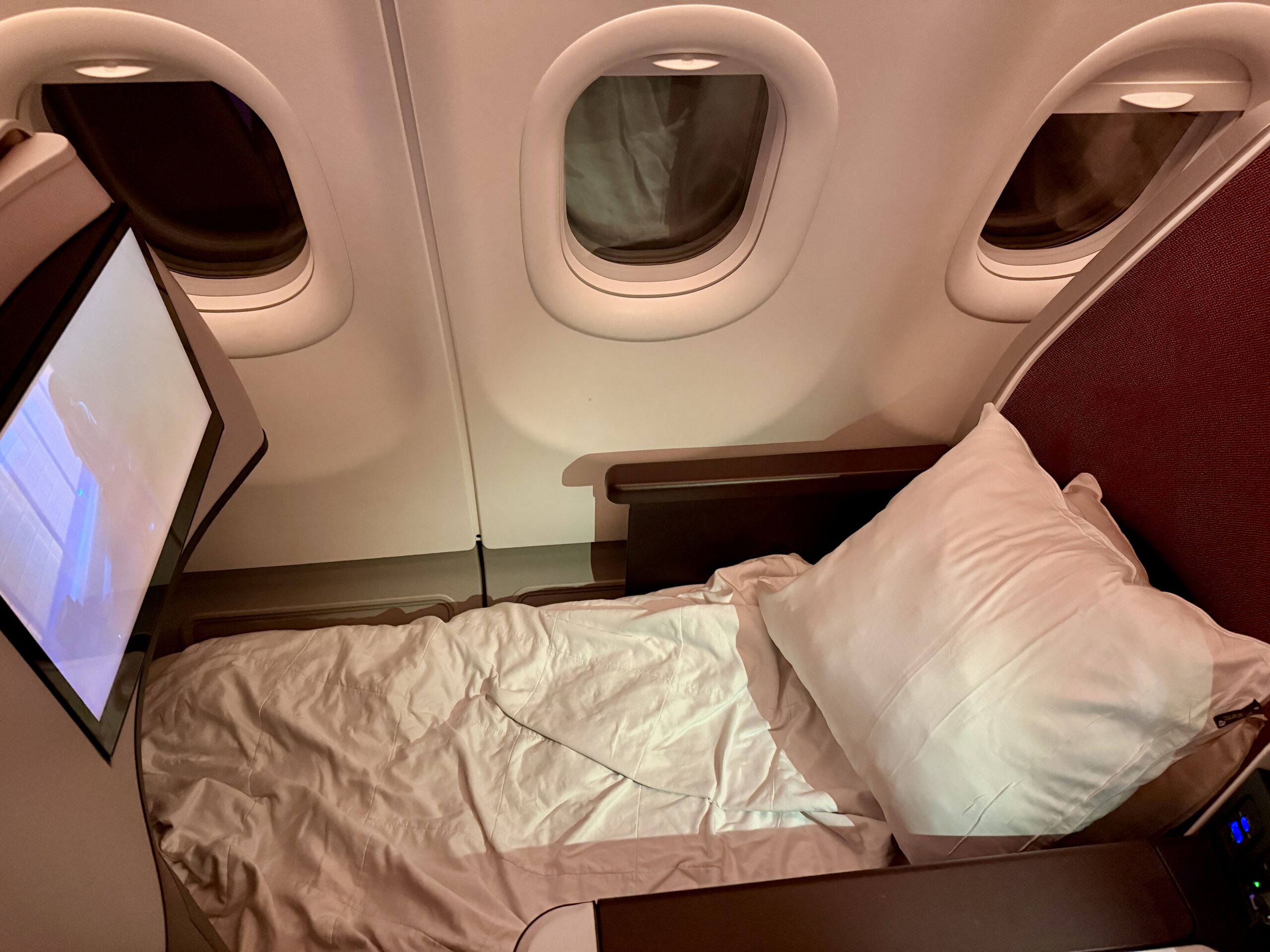 bed on a plane with pillow and blanket