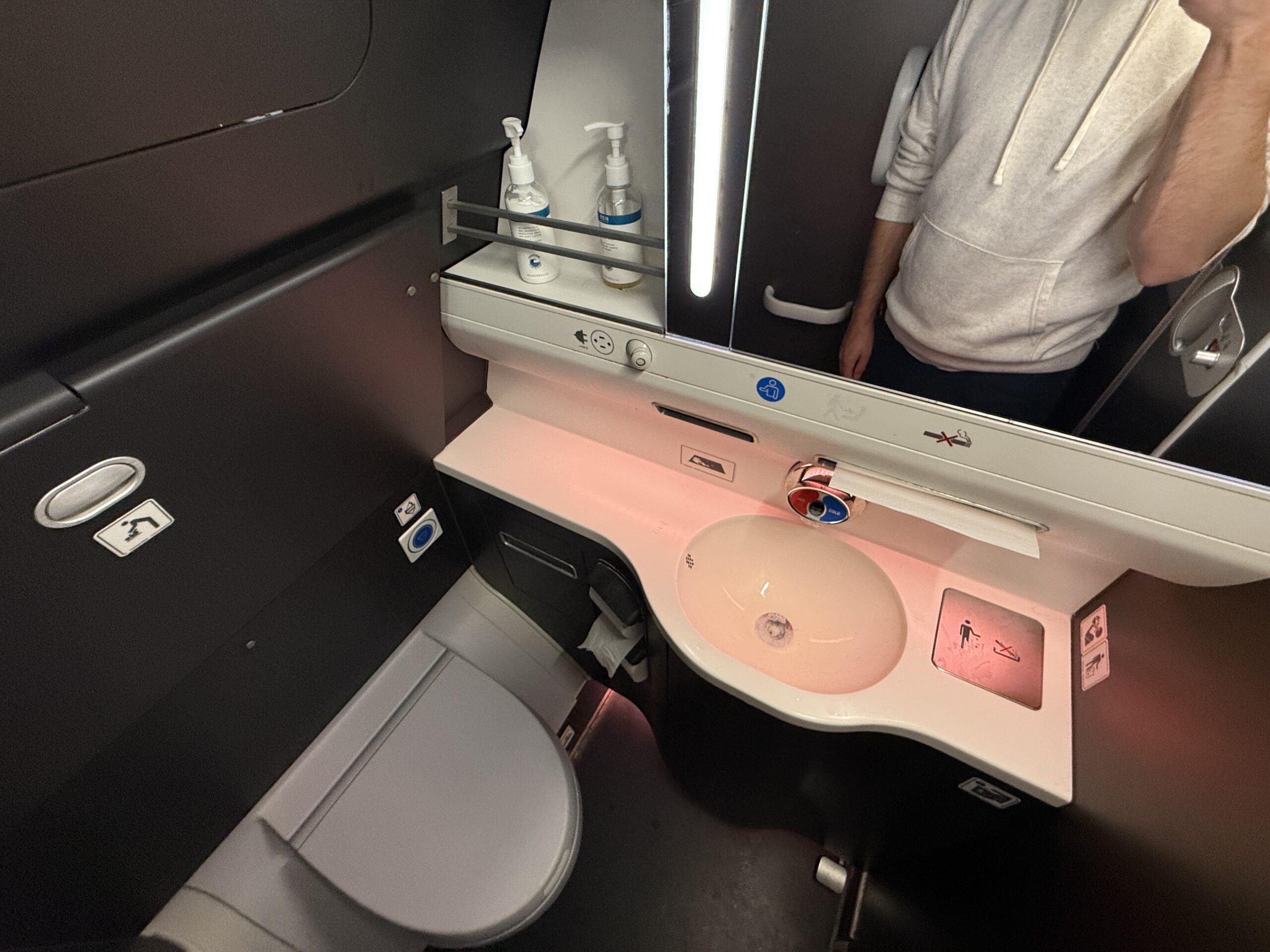 airplane bathroom with a person in the mirror