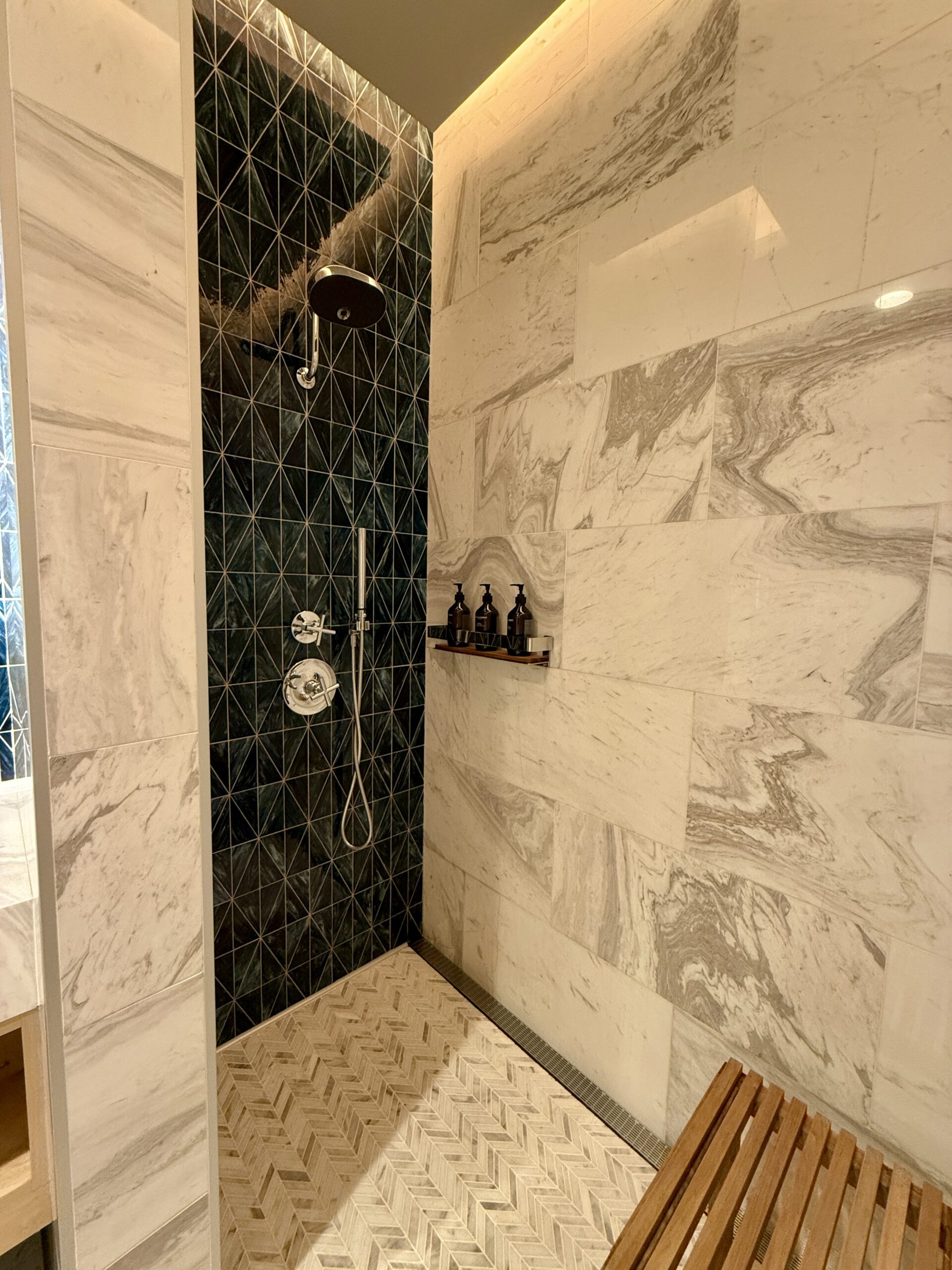 large tiled shower with a wooden bench