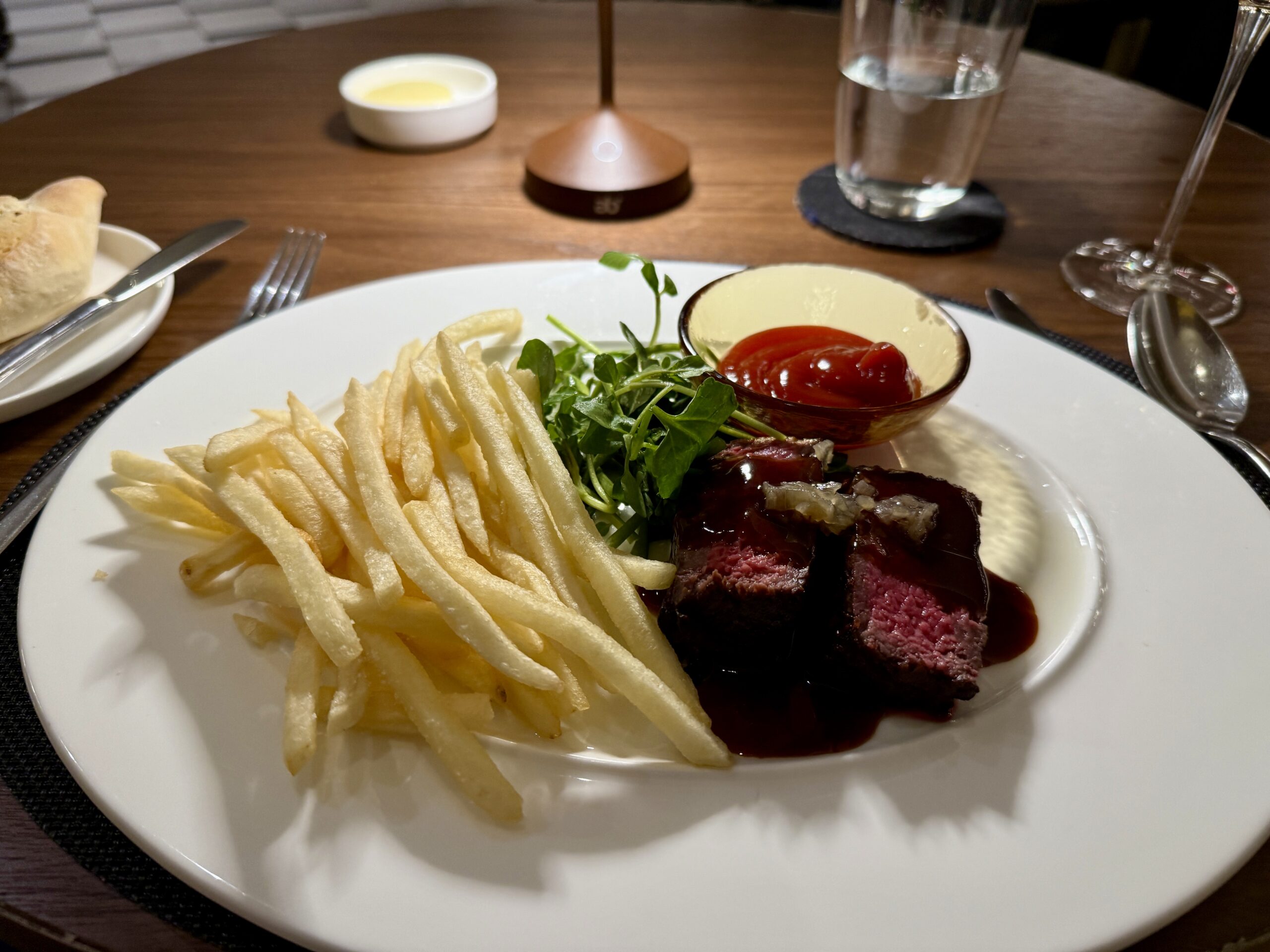 steak on a platter with a side of fries and ketchup