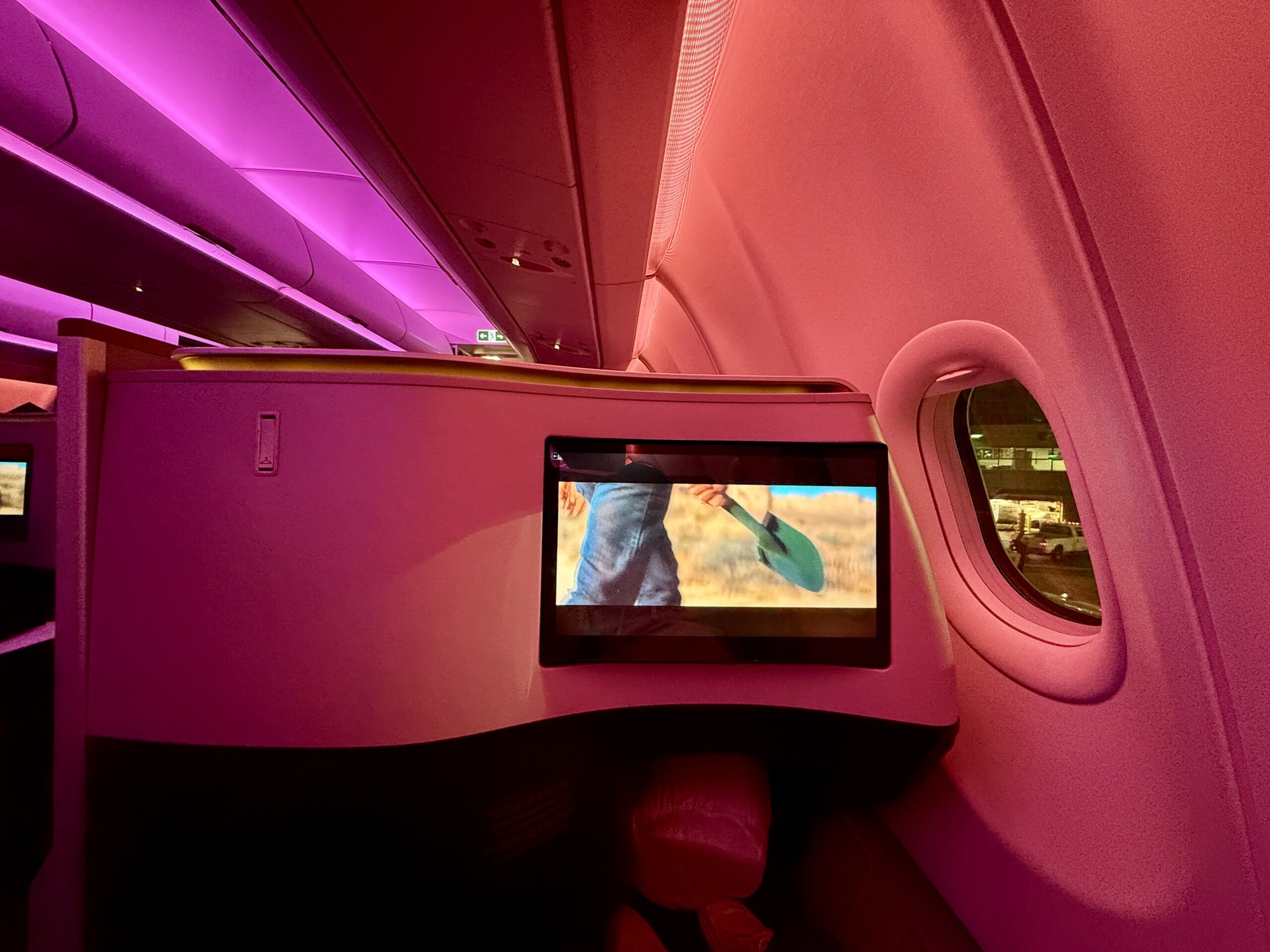 tv screen on a plane with red and purple overhead lighting