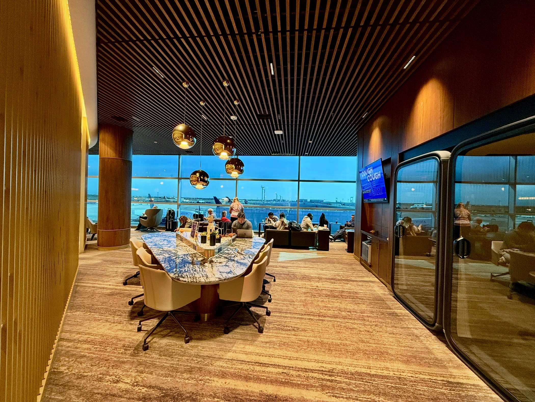 people sitting at a long work table with wood ceiling overhead